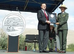 Dave Croft presents first-day production quarters to park superintendent Lisa Carrico